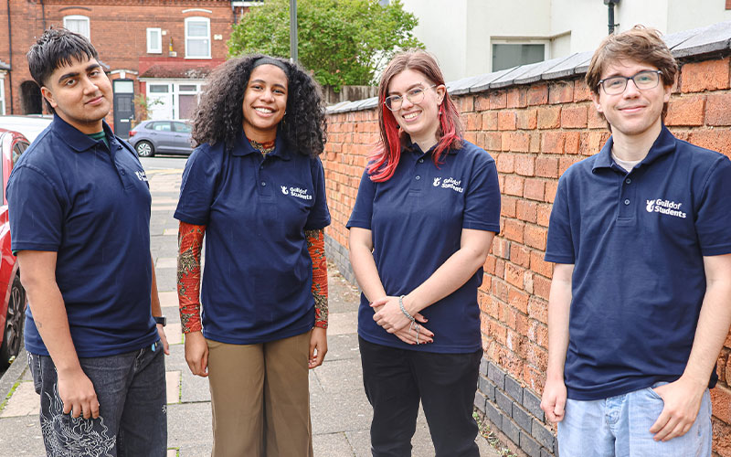 a photo of 4 community ambassadors standing in the street smiling to the camera in blue Guild t-shirts