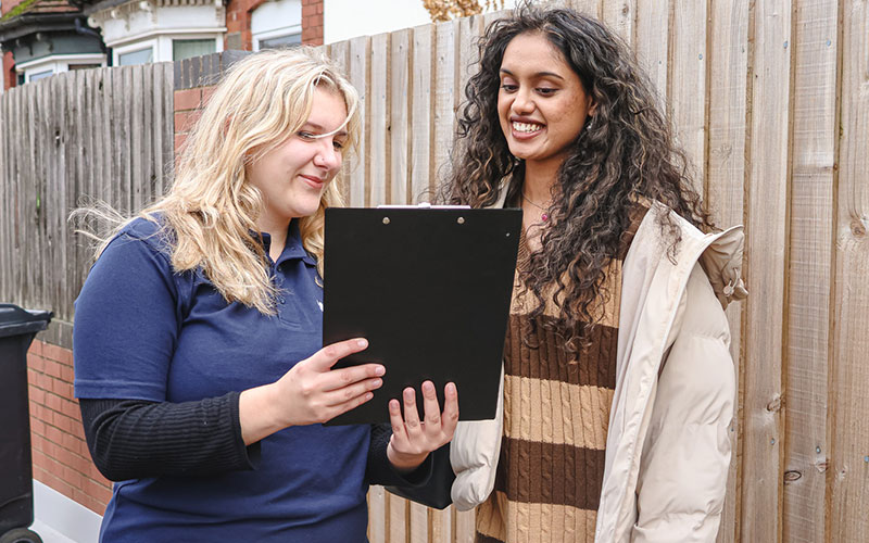 a photo of a community ambassadors showing a student a clipboard