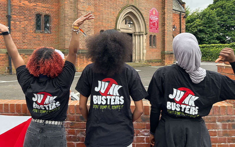 a photo of 3 students facing away from the camera wearing junkbusters tshirts with the logo on the back