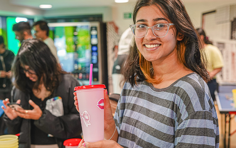 a photo of a student holding a water bottle decorated at a crafts event