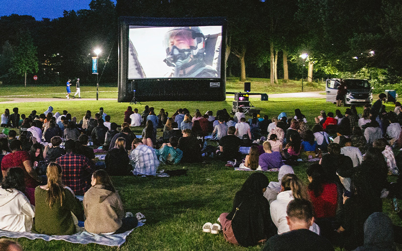 a photo of the open air cinema with a crowd of students sitting down watching a screen