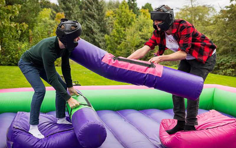 a photo of 2 students on an inflatable platform with 2 inflatable sticks