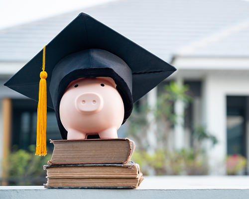 a piggy bank with a graduate hat on top of some books