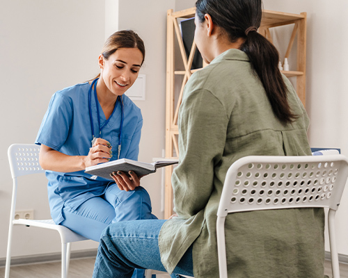 a student talking to a nurse sitting down in chairs