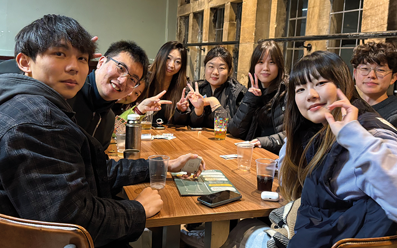 a photo of a group of students sat a table smiling at the camera