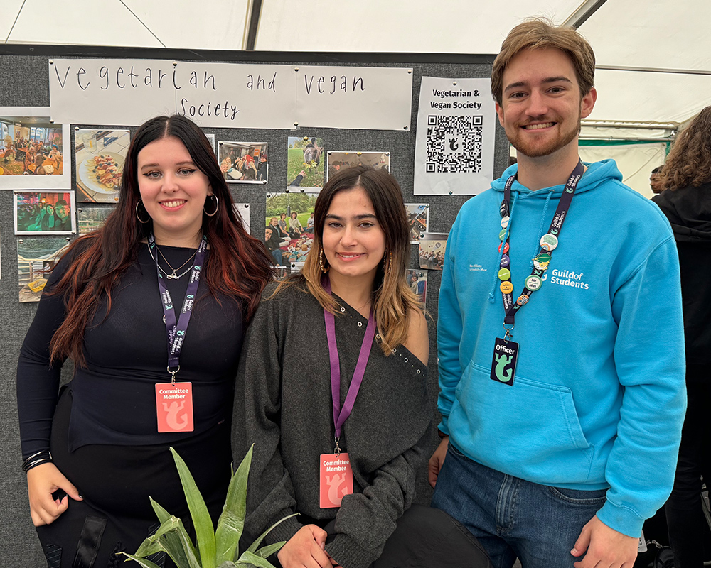 a photo of a students underneath a sign that says Vegetarian and Vegan Society