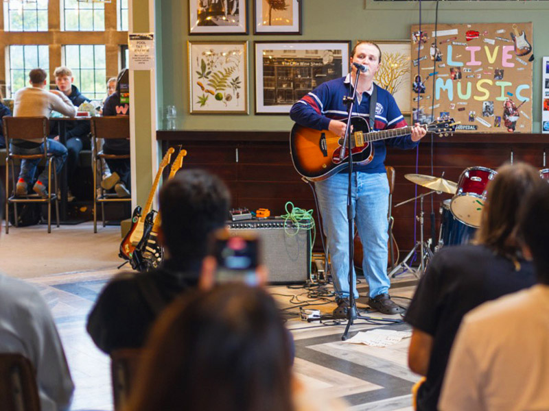 an image of student singing with a guitar in joe's bar