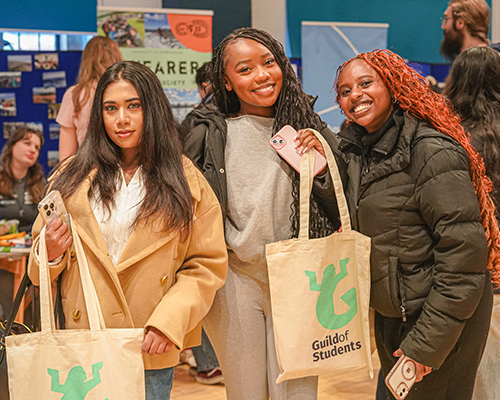 3 students holding guild tote bags