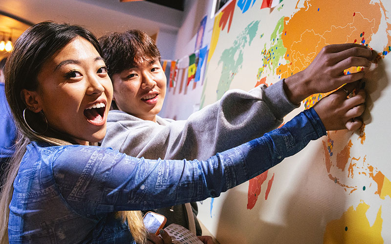students at a international event pointing at a map